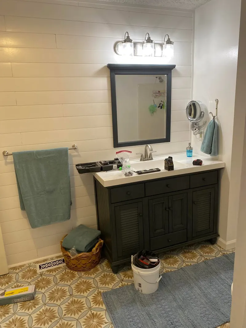 Finished bathroom vanity with dark cabinetry and patterned tile floor